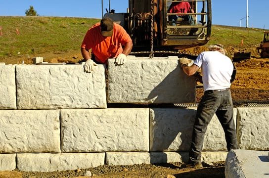 Texas Land Keepers crew setting large limestone blocks for a retaining wall