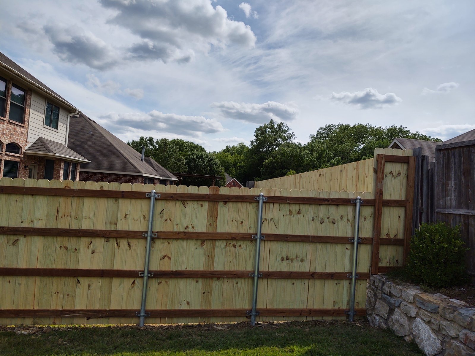 Metal sliding driveway gate open beside a paved drive
